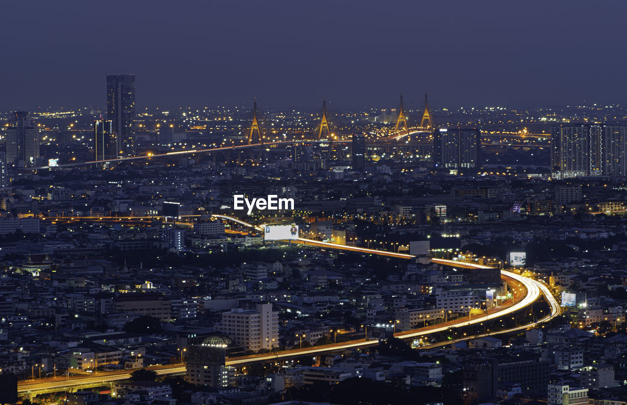 HIGH ANGLE VIEW OF ILLUMINATED BUILDINGS AT NIGHT