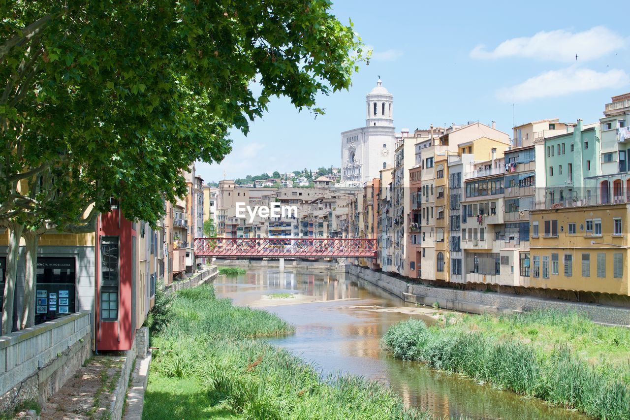 Buildings by river against sky in city