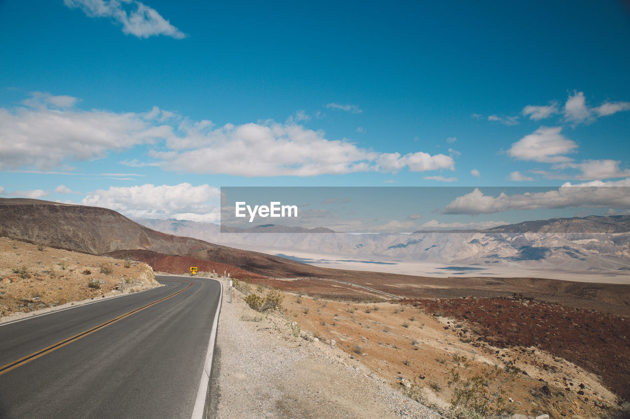 Road by mountains against sky
