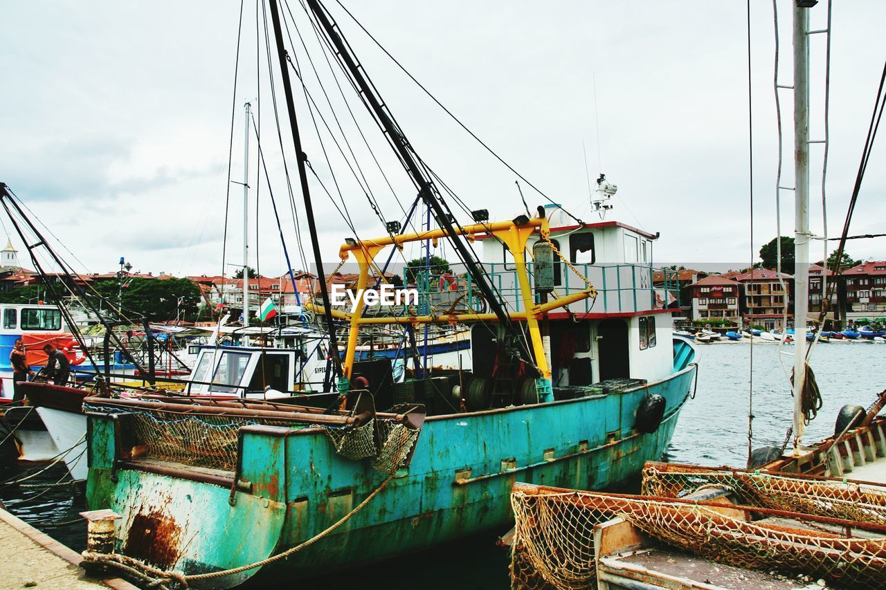 Boats moored at harbor against sky