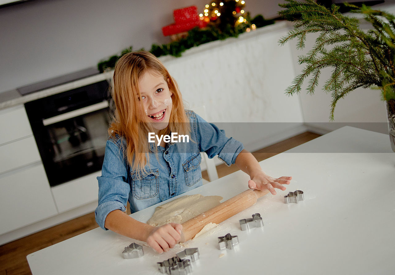 Happy little girl cooks christmas cookies at home in the kitchen . small blonde is preparing cookies 