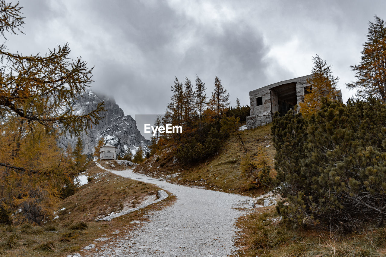 cloud, tree, winter, snow, sky, plant, nature, architecture, autumn, landscape, mountain, wilderness, environment, rural area, scenics - nature, land, building, built structure, building exterior, no people, mountain range, beauty in nature, overcast, house, travel, forest, coniferous tree, pinaceae, travel destinations, pine tree, road, non-urban scene, outdoors, storm, cold temperature, tourism, water, pine woodland, footpath, rural scene, tranquility