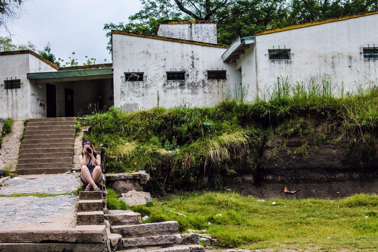 Woman photographing on steps against building