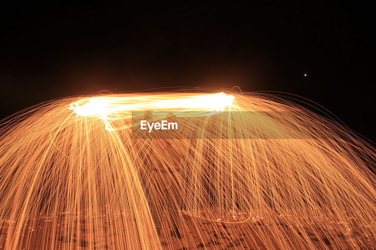 Man spinning wire wool at night