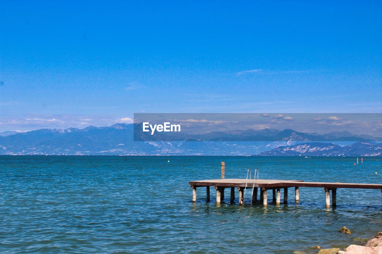 Pier over sea against blue sky