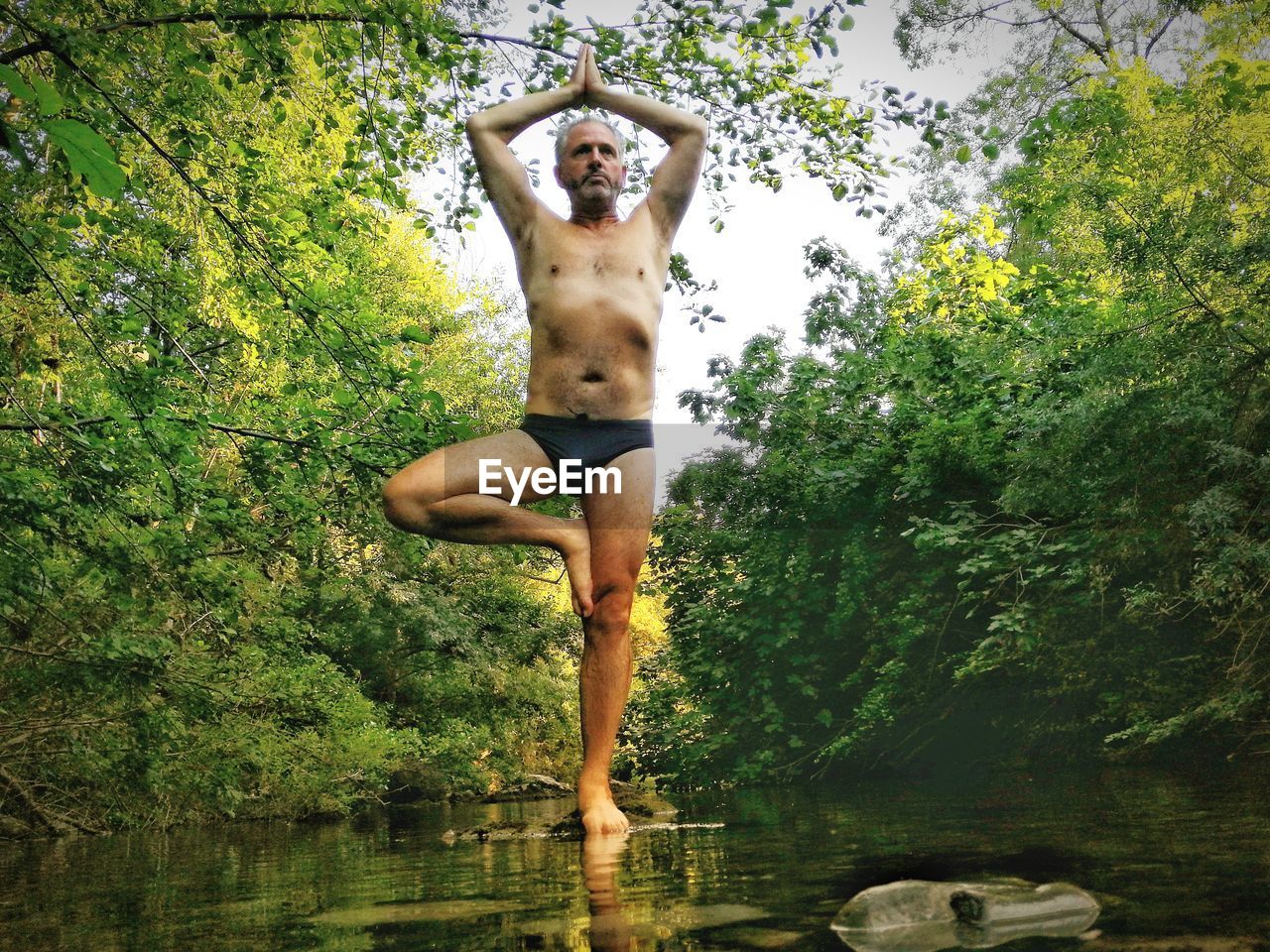 Full length of shirtless man in yoga tree pose