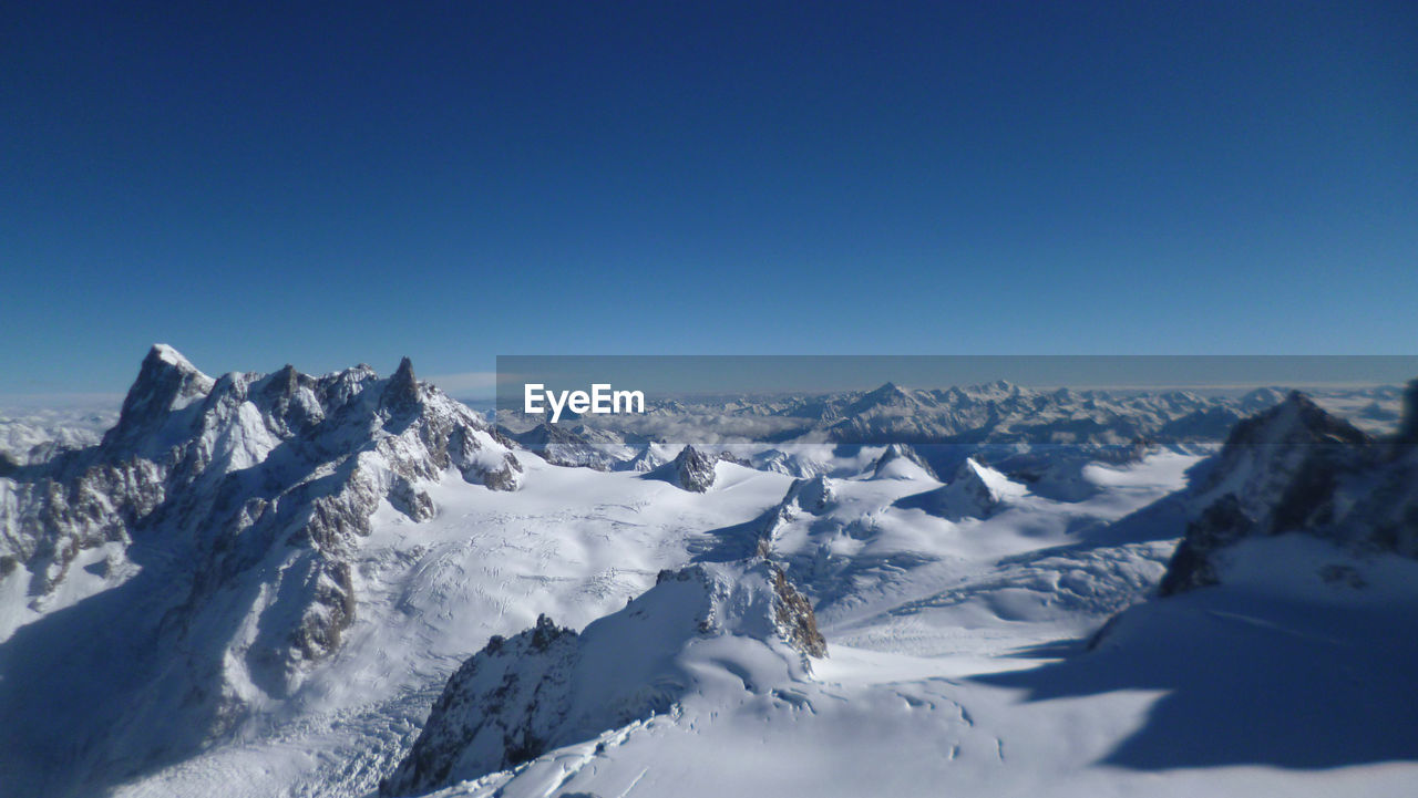 Scenic view of snowcapped mountains during sunny day