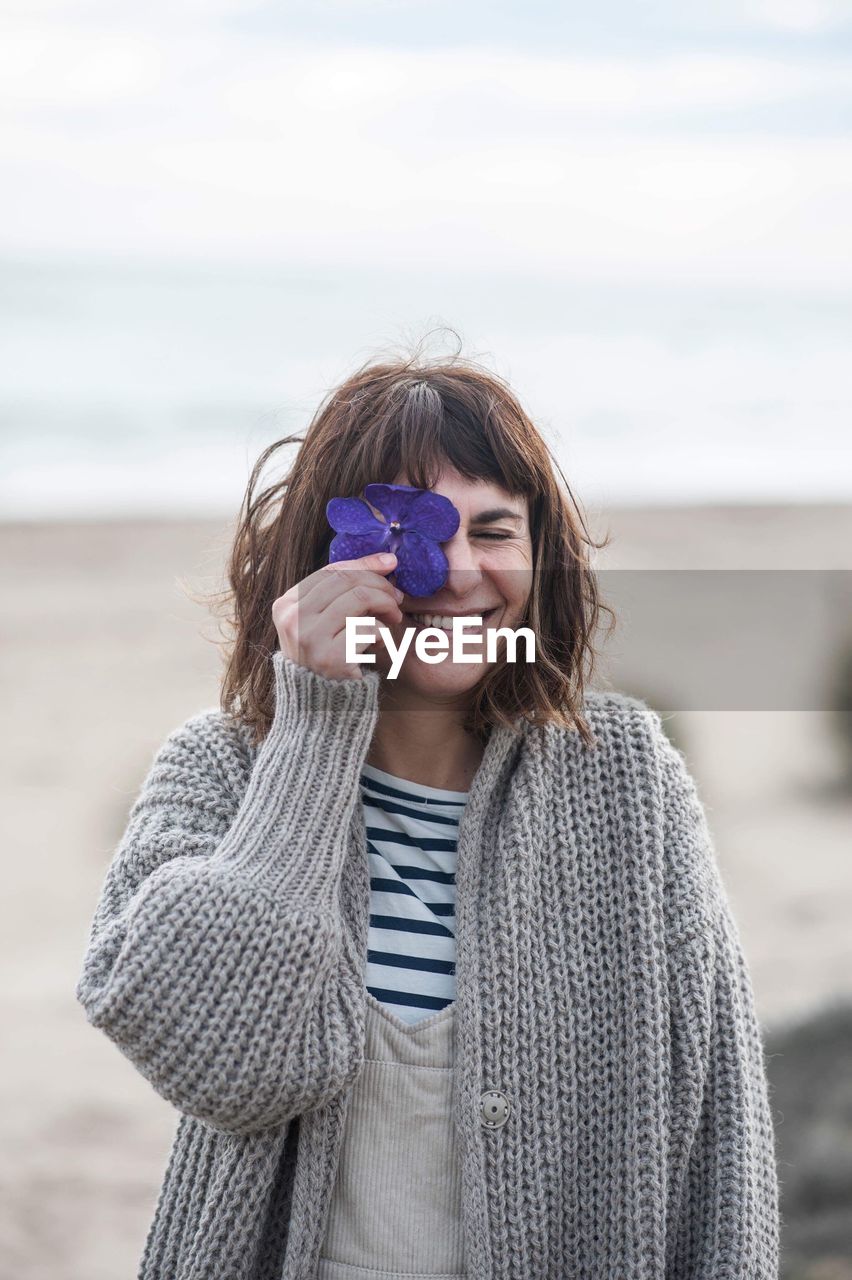 Smiling woman holding flower at beach