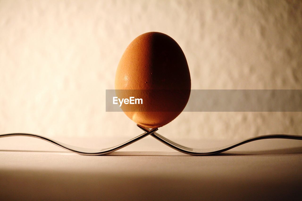 Close-up of egg over forks on table