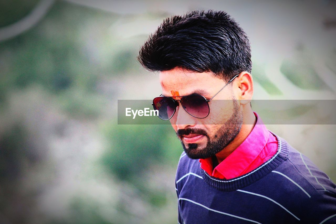 Young man wearing sunglasses while standing outdoors