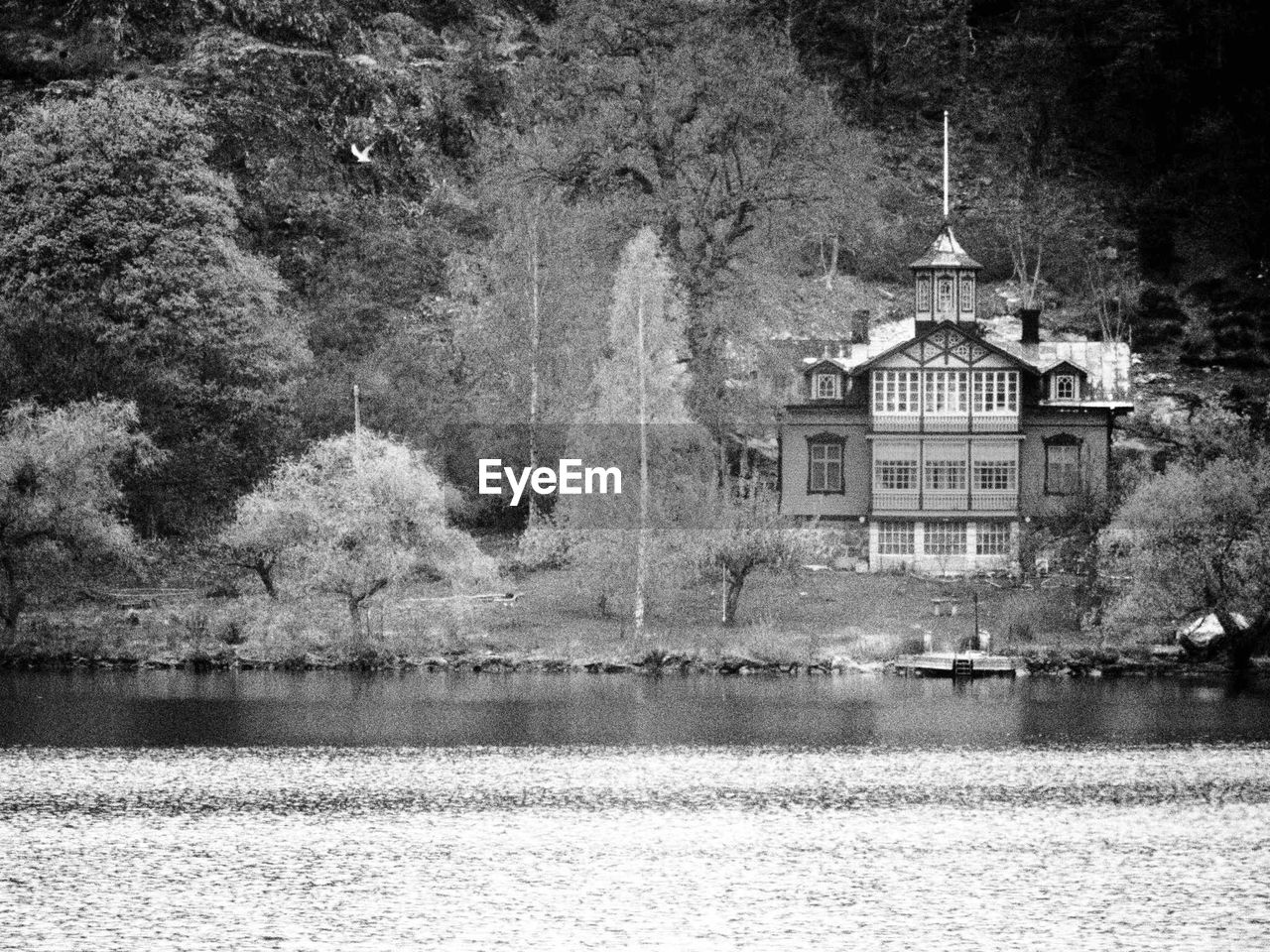 BUILT STRUCTURE BY RIVER AGAINST TREES