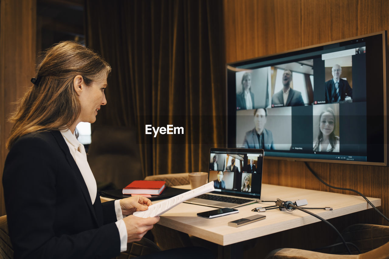 Businesswoman discussing with male and female colleagues on video call through laptop in office