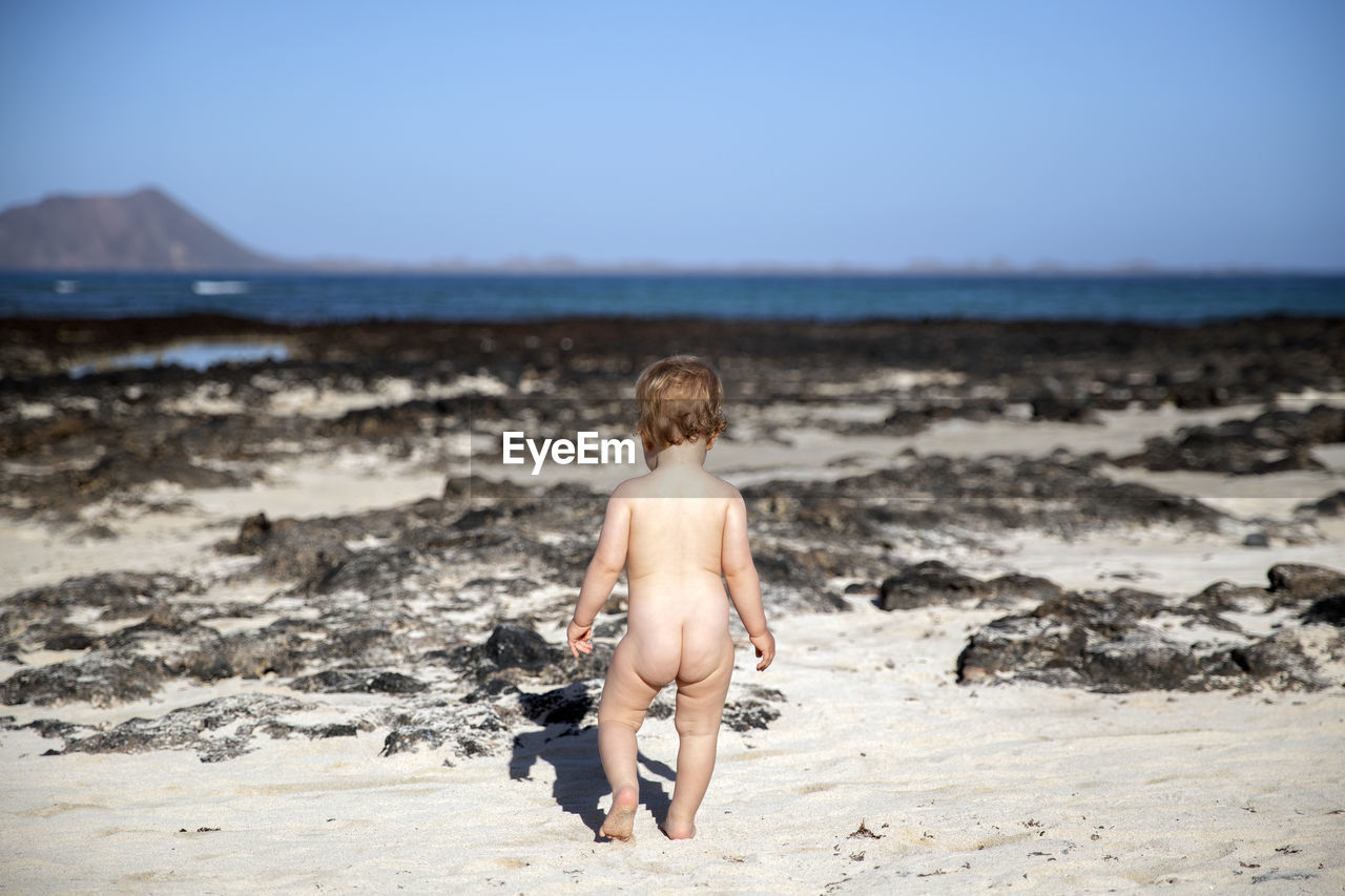 FULL LENGTH OF SHIRTLESS BOY ON SHORE