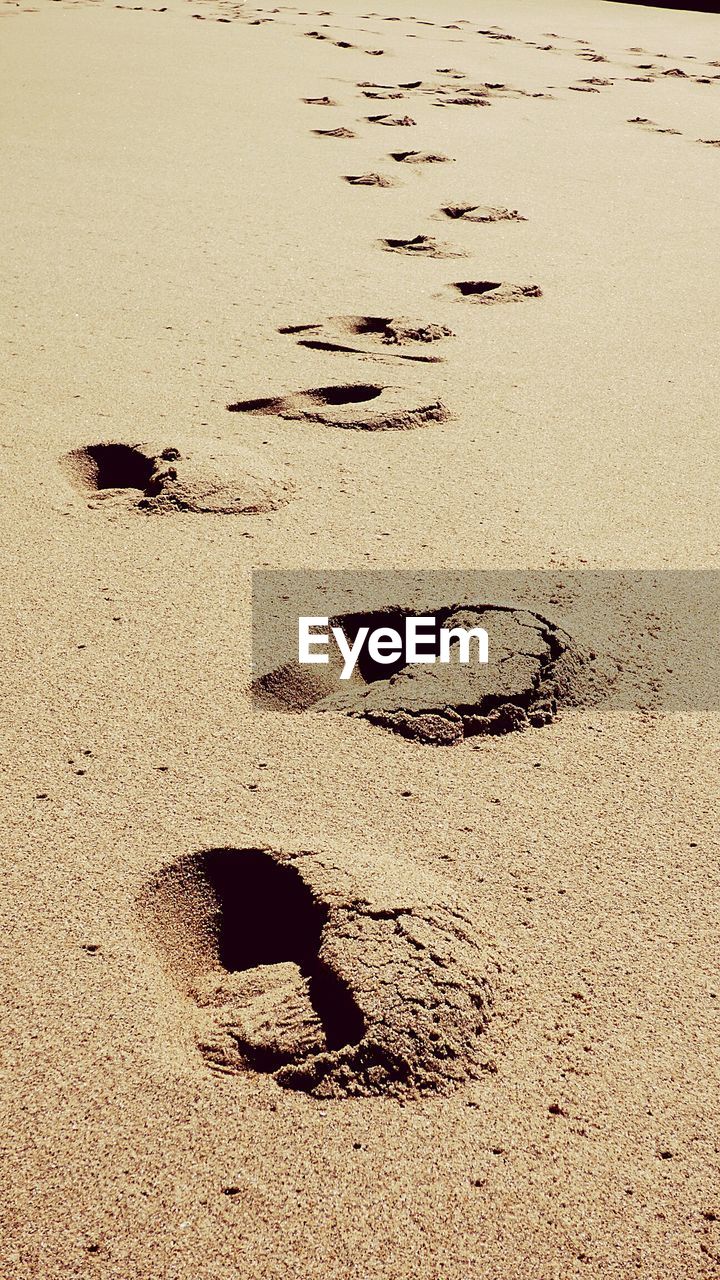 Footprint on sand during sunny day