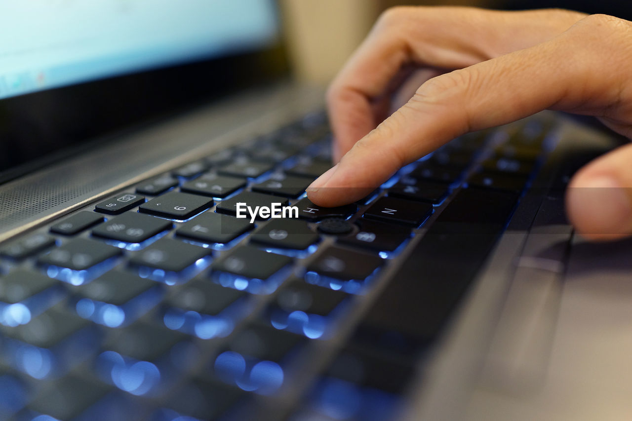 Cropped hand of man using laptop