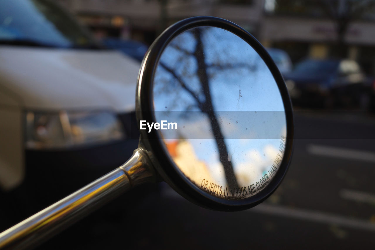 CLOSE-UP OF EYEGLASSES ON SIDE-VIEW MIRROR OF CAR