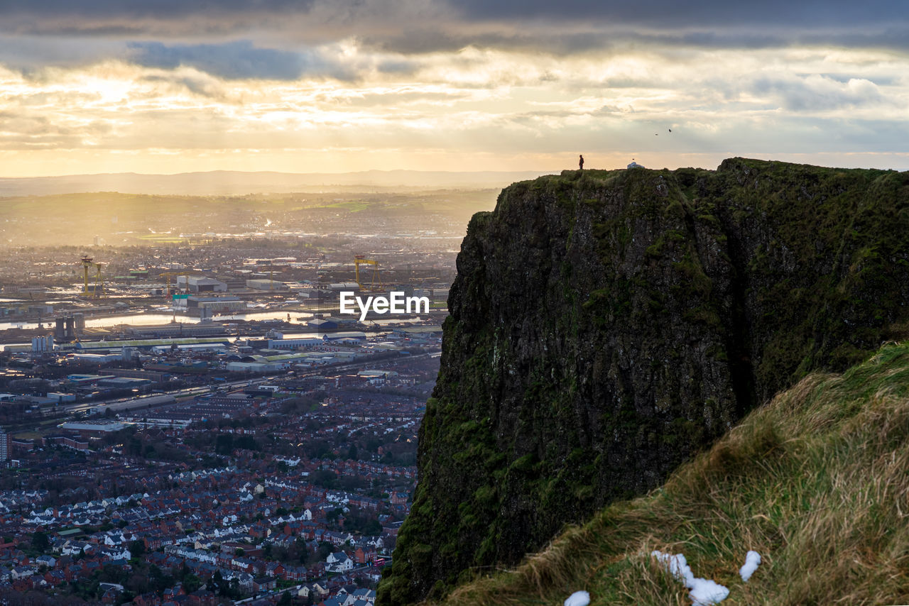 Scenic view of mountains and buildings against sky at sunset