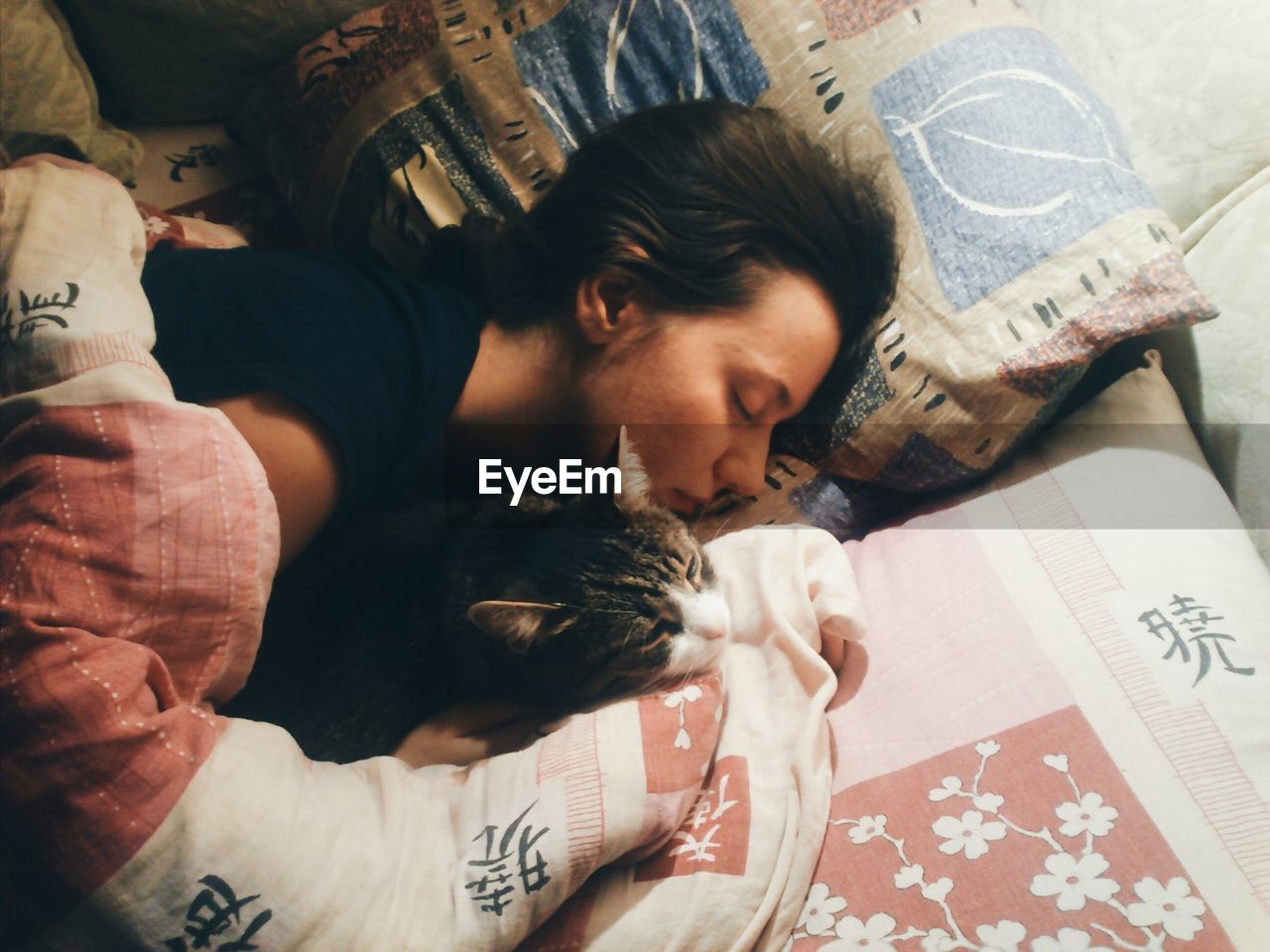 High angle view of young woman sleeping with cat on bed