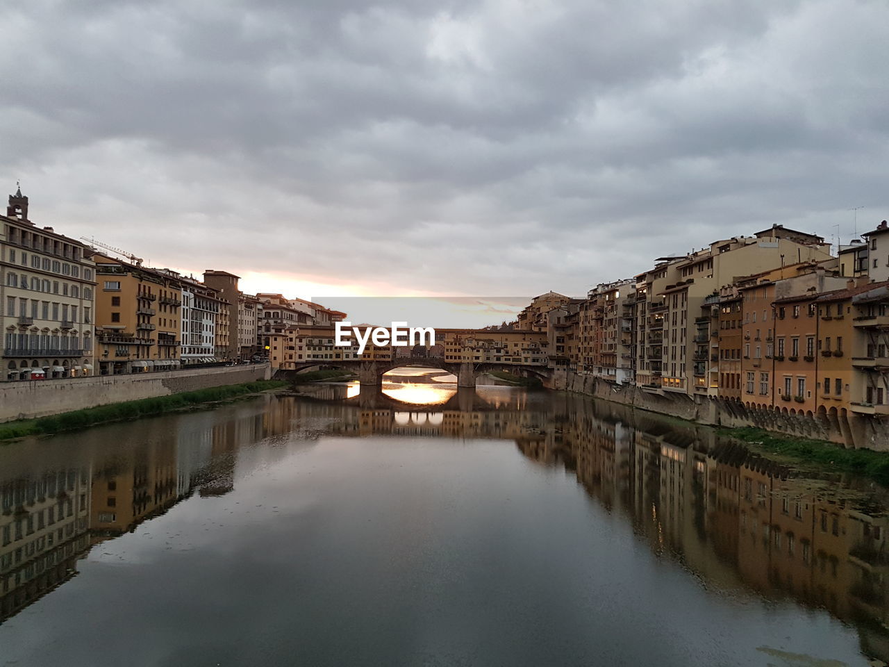 Bridge over river by buildings against sky in city