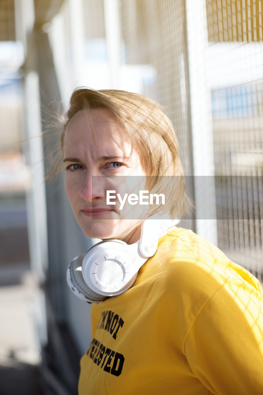 Portrait of woman standing by fence