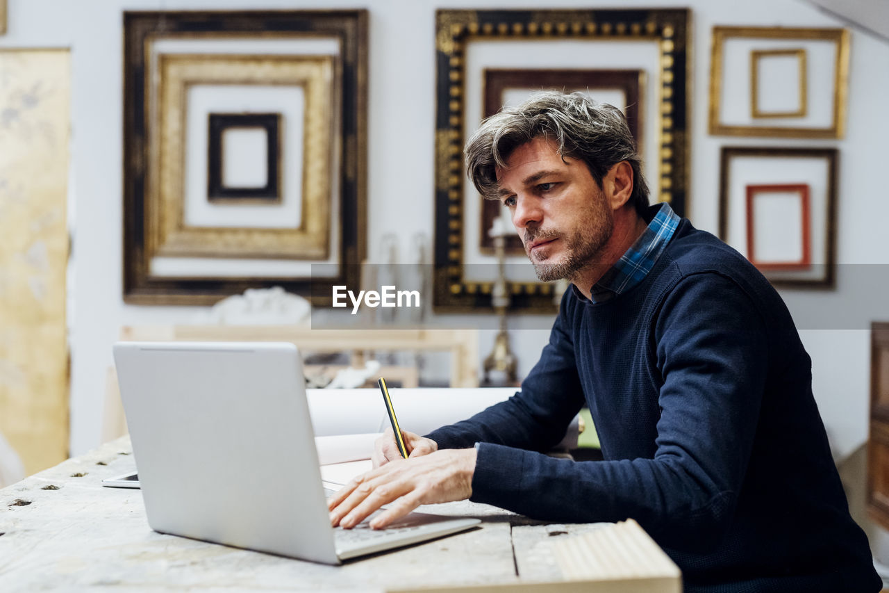 Mature man using laptop working in workshop