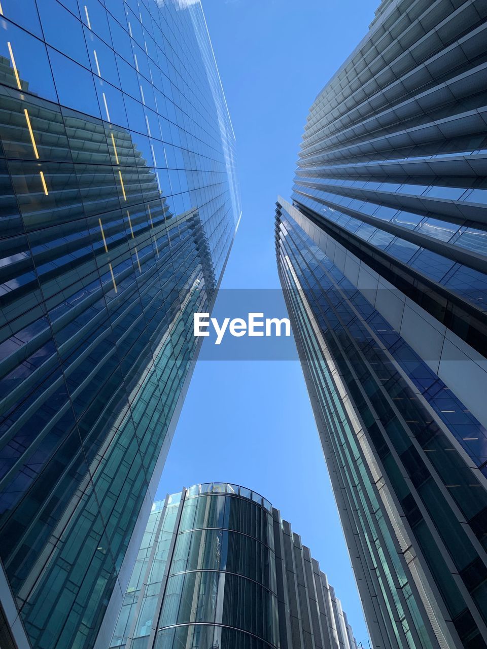 LOW ANGLE VIEW OF MODERN GLASS BUILDINGS AGAINST CLEAR SKY