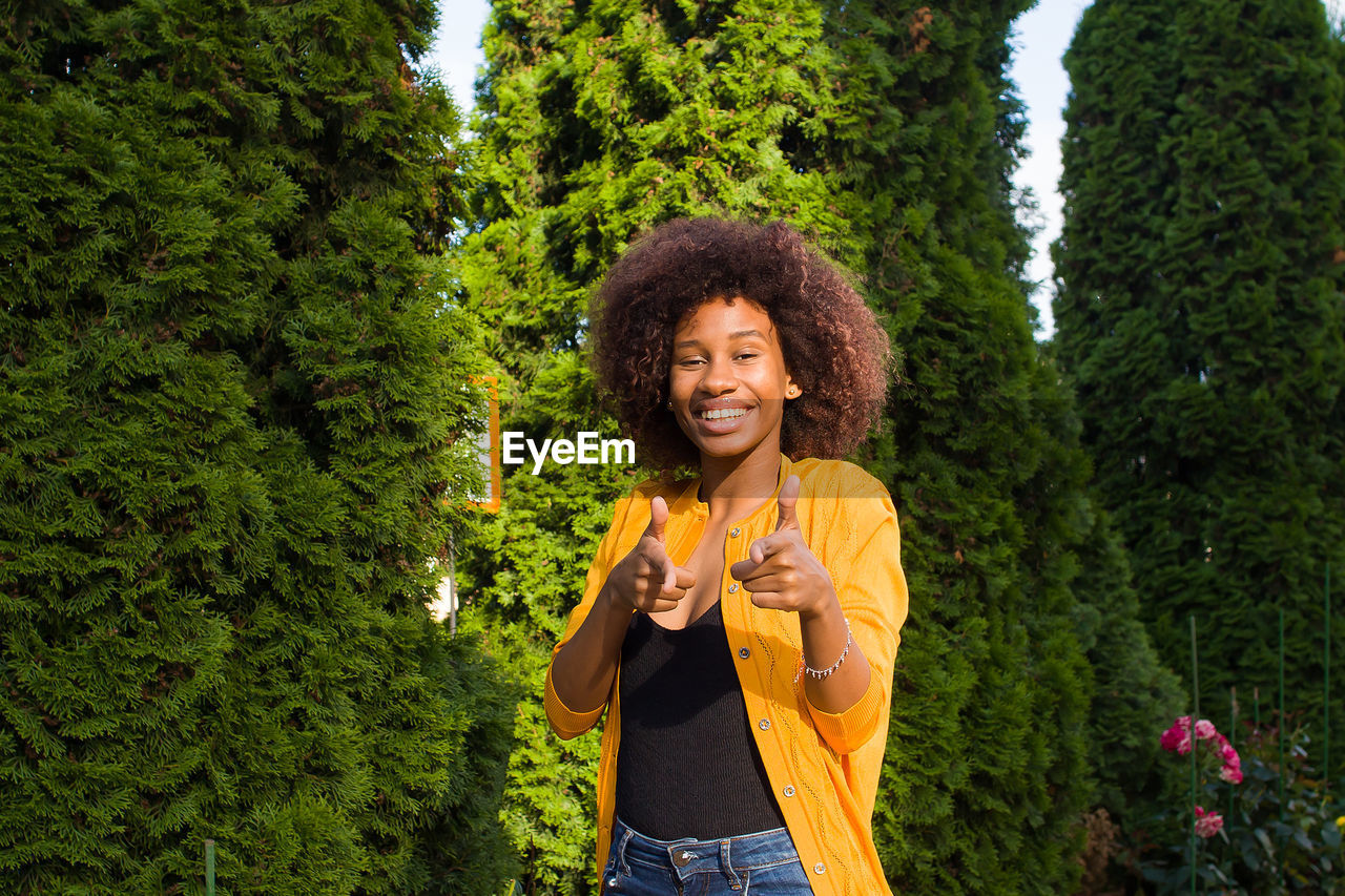HAPPY WOMAN STANDING AGAINST TREES
