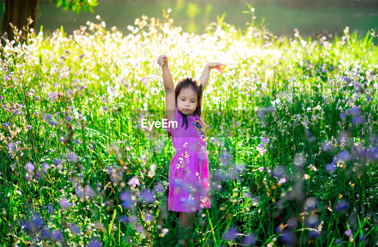 Girl standing amidst flowers on land