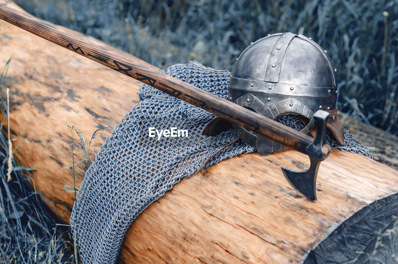 Metal chain mail, helmet and ax lie on wooden log. viking armor. historical film concept.