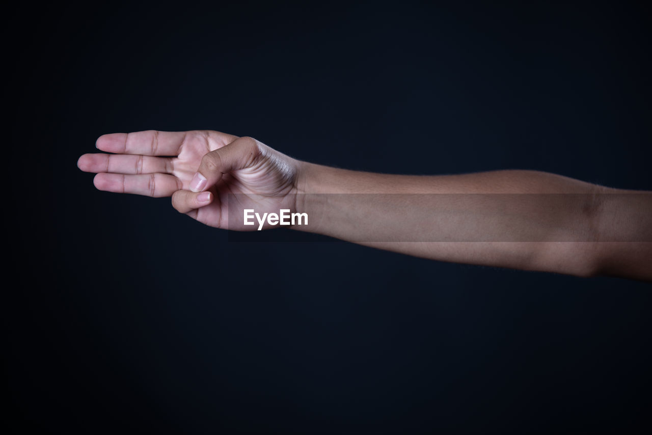 CLOSE-UP OF HANDS AGAINST BLACK BACKGROUND