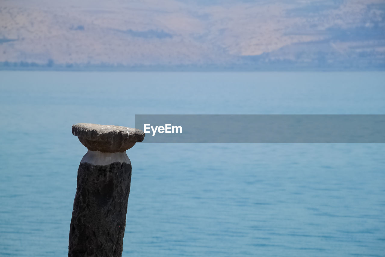 WOODEN POST ON SEA AGAINST SKY