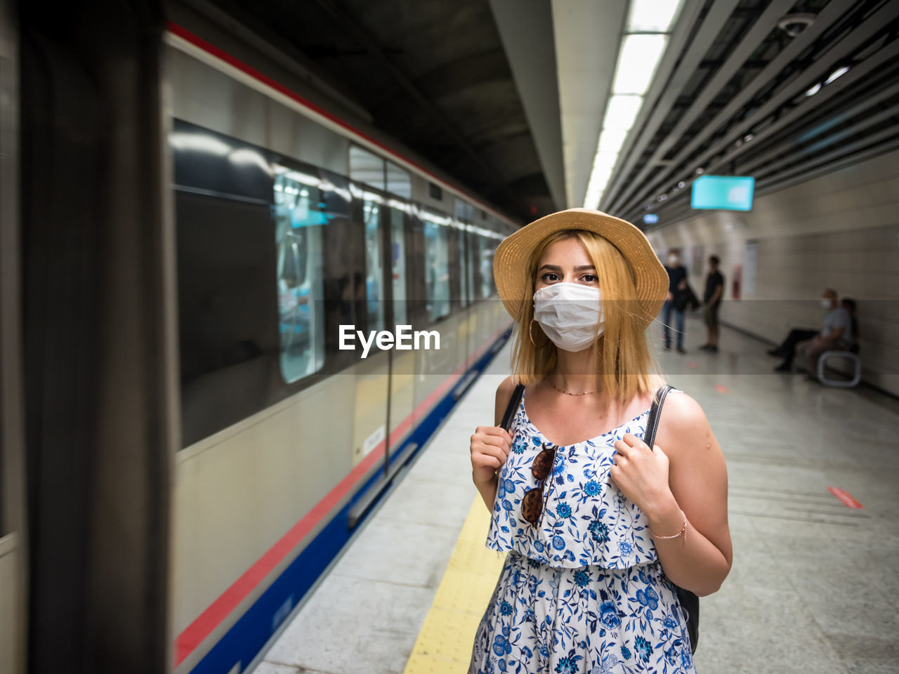 Portrait of woman wearing mask while standing at railroad station platform