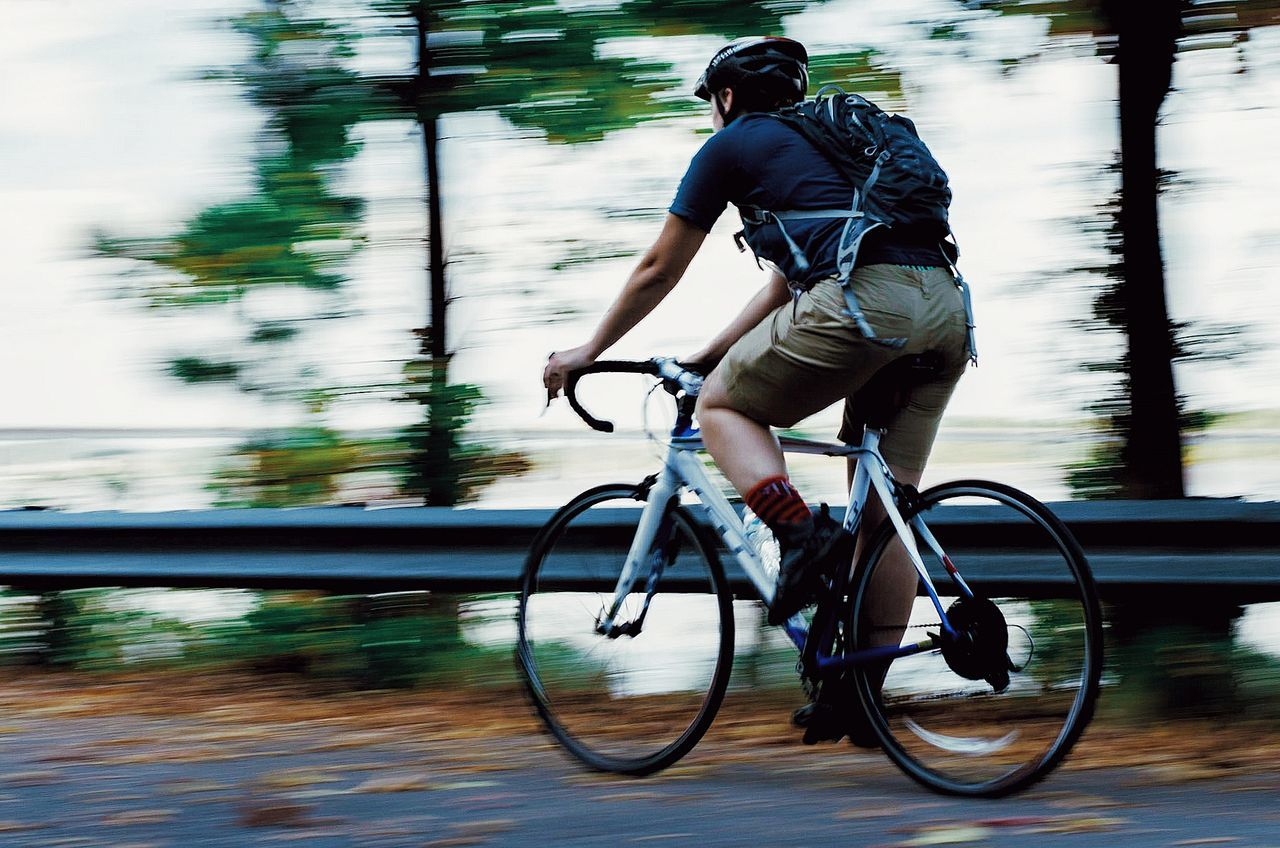 Blurred motion of young woman riding bicycle on road