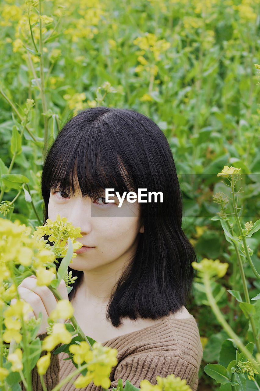 Portrait of woman smelling yellow flowers