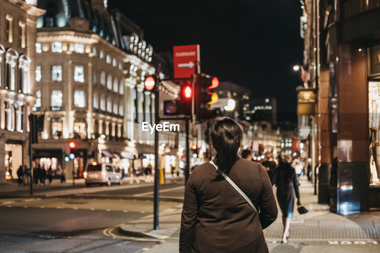 Rear view of a woman waiting for a green light on regent street, london, uk.