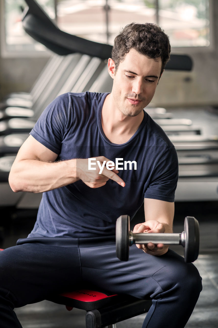 Lifestyle playful man having fun lifting dumbbell in gym exercise with work out program for healthy.