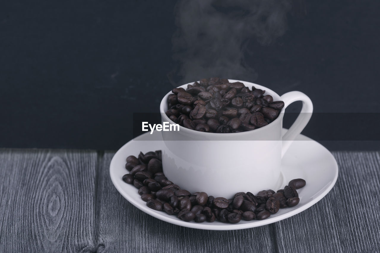 CLOSE-UP OF COFFEE CUP ON TABLE AGAINST WALL