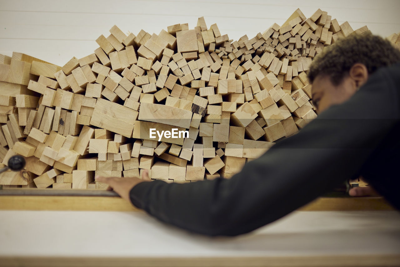 Young female carpenter arranging planks on rack in industry