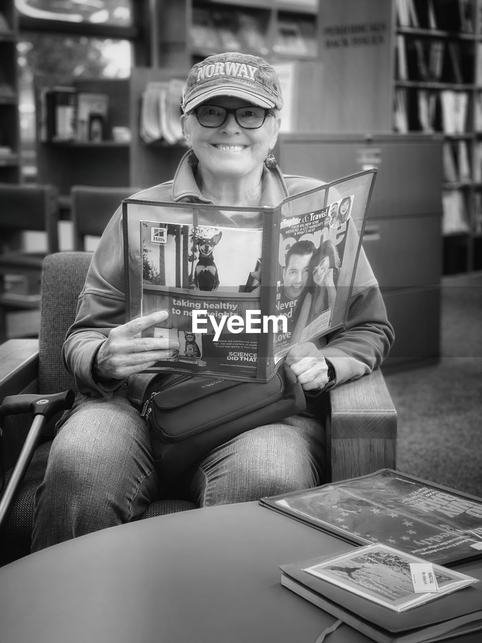 white, black, one person, sitting, black and white, monochrome, book, monochrome photography, adult, publication, front view, indoors, reading, person, portrait, glasses, activity, clothing, lifestyles, furniture, holding, men, casual clothing, leisure activity, technology, looking at camera, relaxation, smiling, occupation, child, table, human face, business, women, arts culture and entertainment