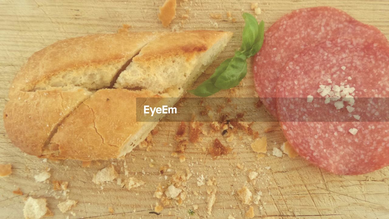 Baguette and salami on cutting board