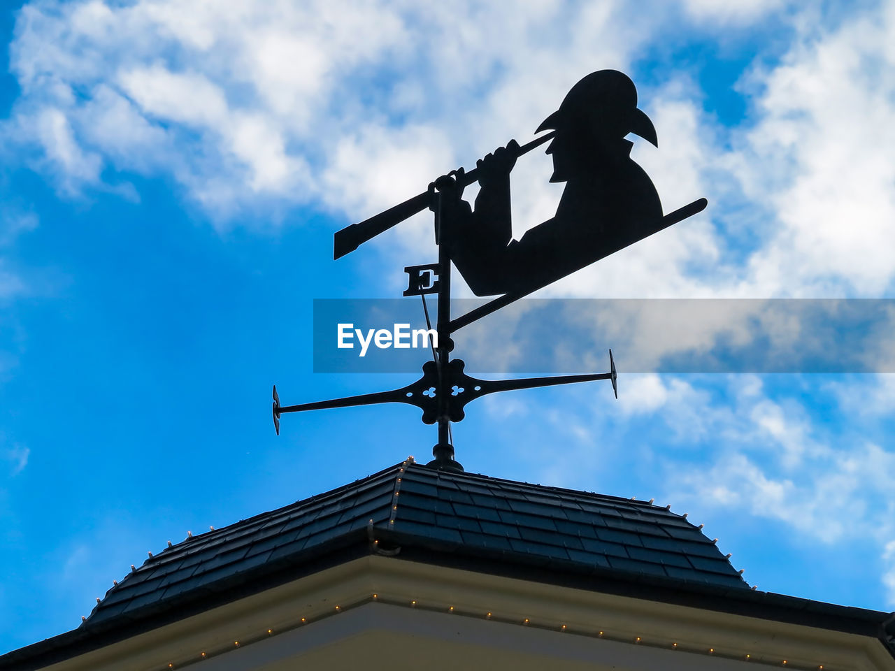 A weather vane with person looking through a telescope