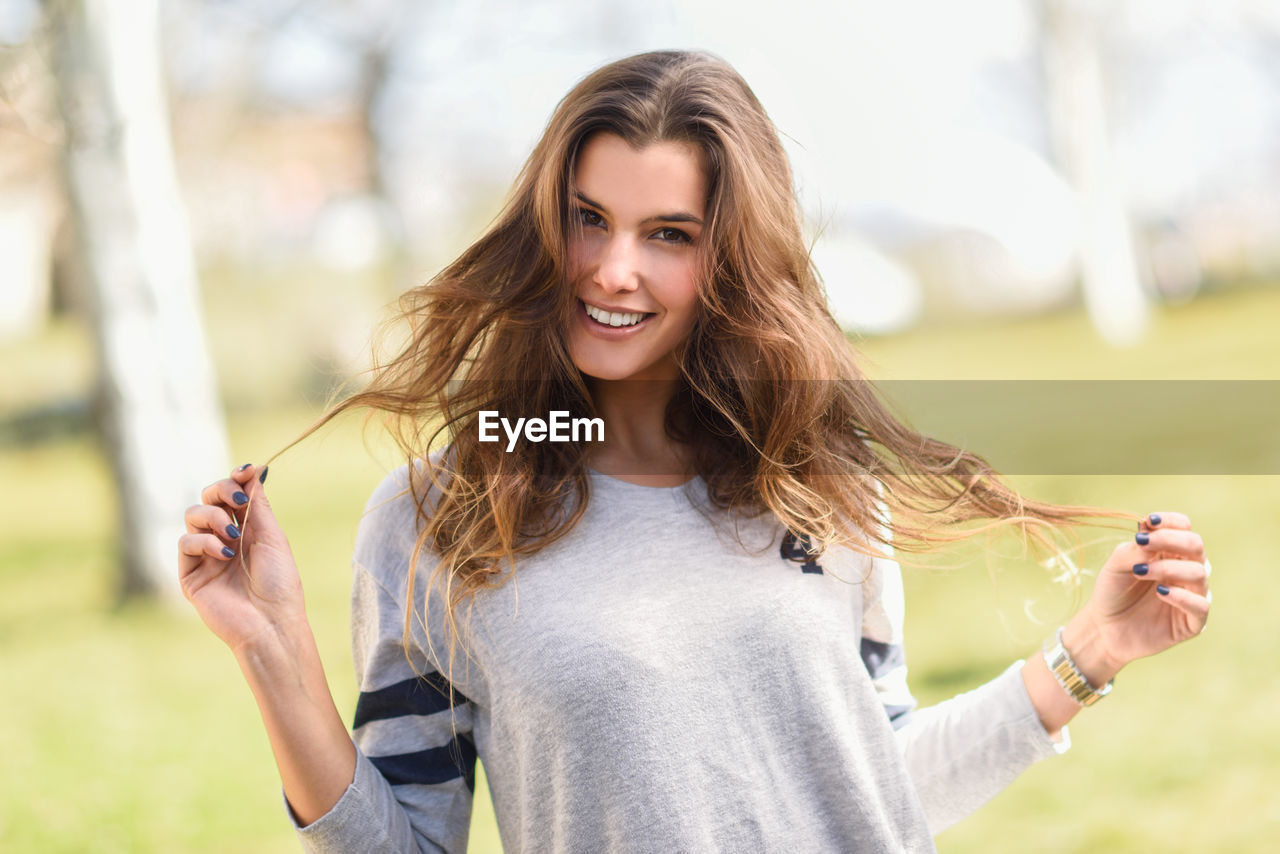 Portrait of smiling young woman standing on field