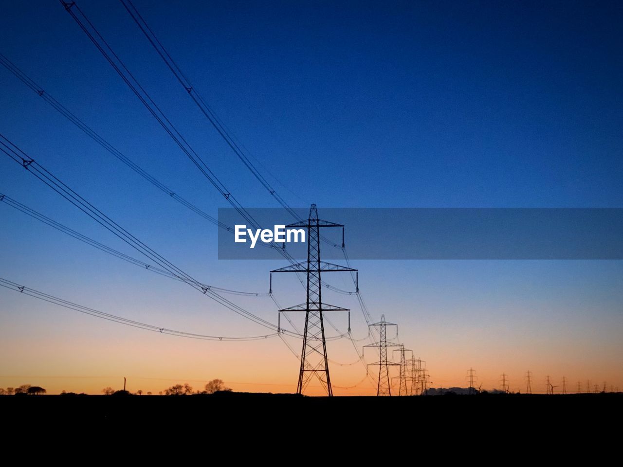 SILHOUETTE ELECTRICITY PYLONS AGAINST CLEAR SKY AT SUNSET