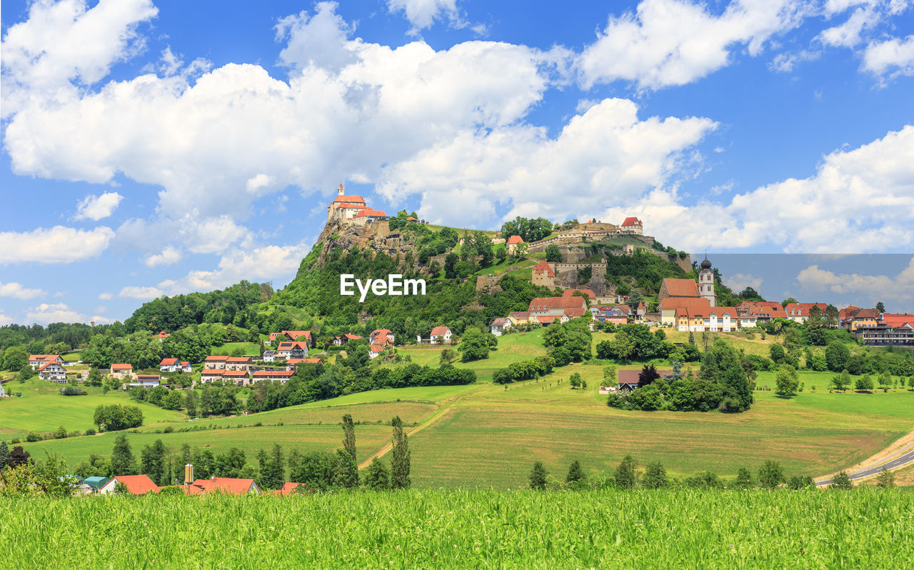 PANORAMIC VIEW OF AGRICULTURAL FIELD AGAINST BUILDINGS