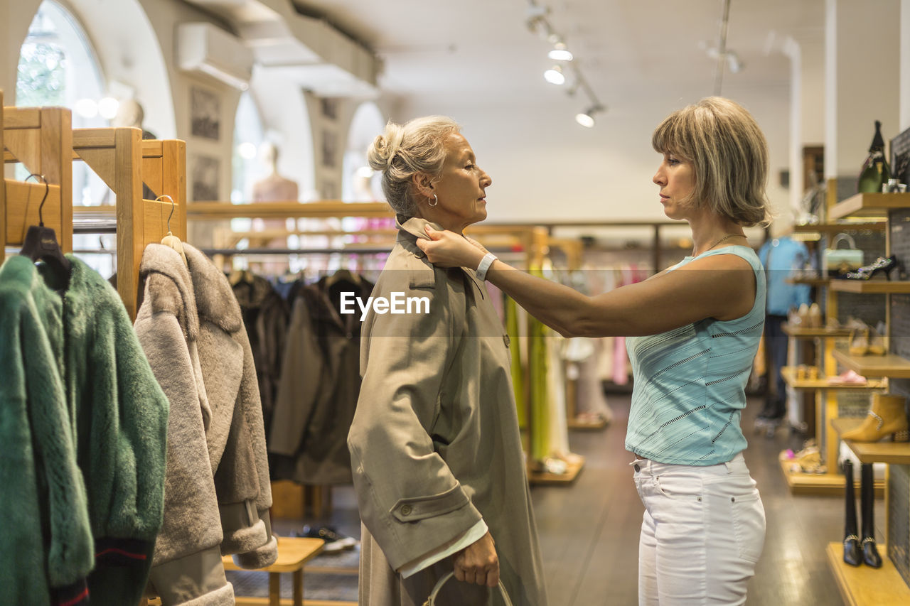 Senior woman trying on coat in a boutique