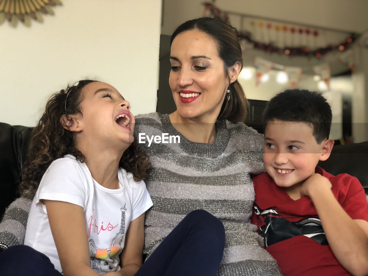 Happy mother with children sitting on sofa at home