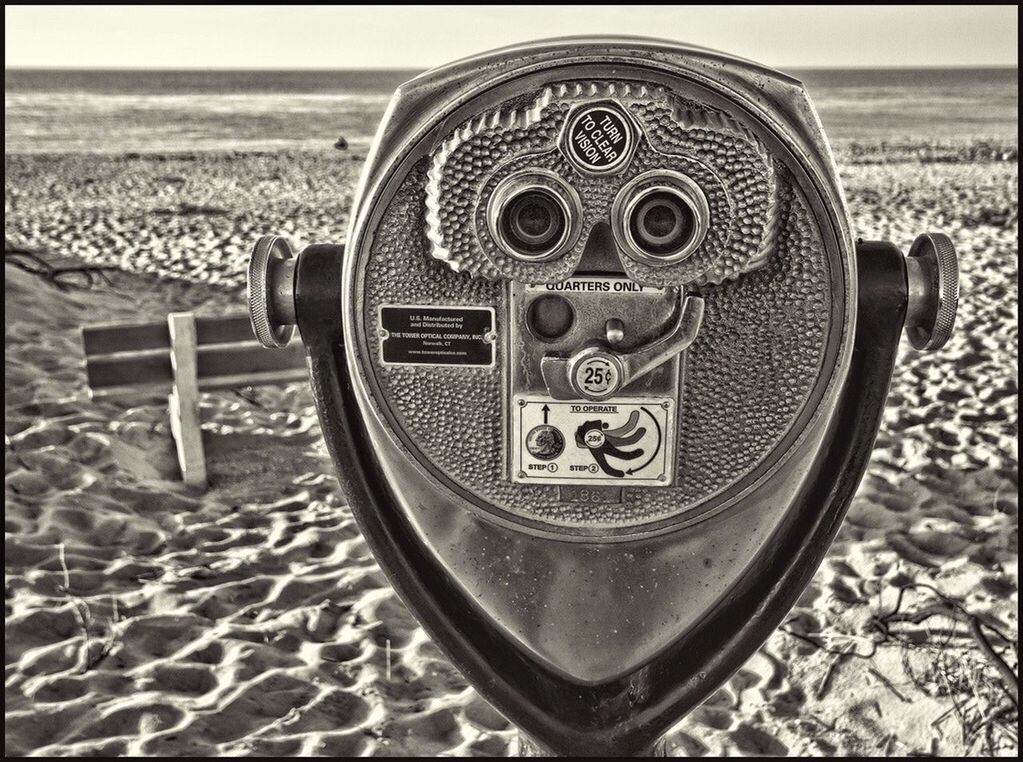 Close-up of coin-operated binocular against sandy beach