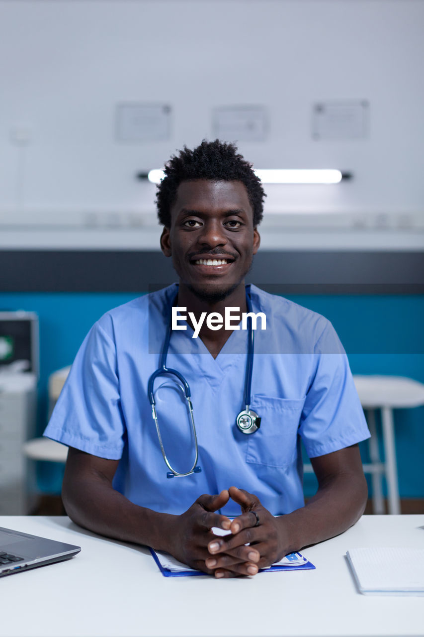 Confident doctor sitting at desk in hospital