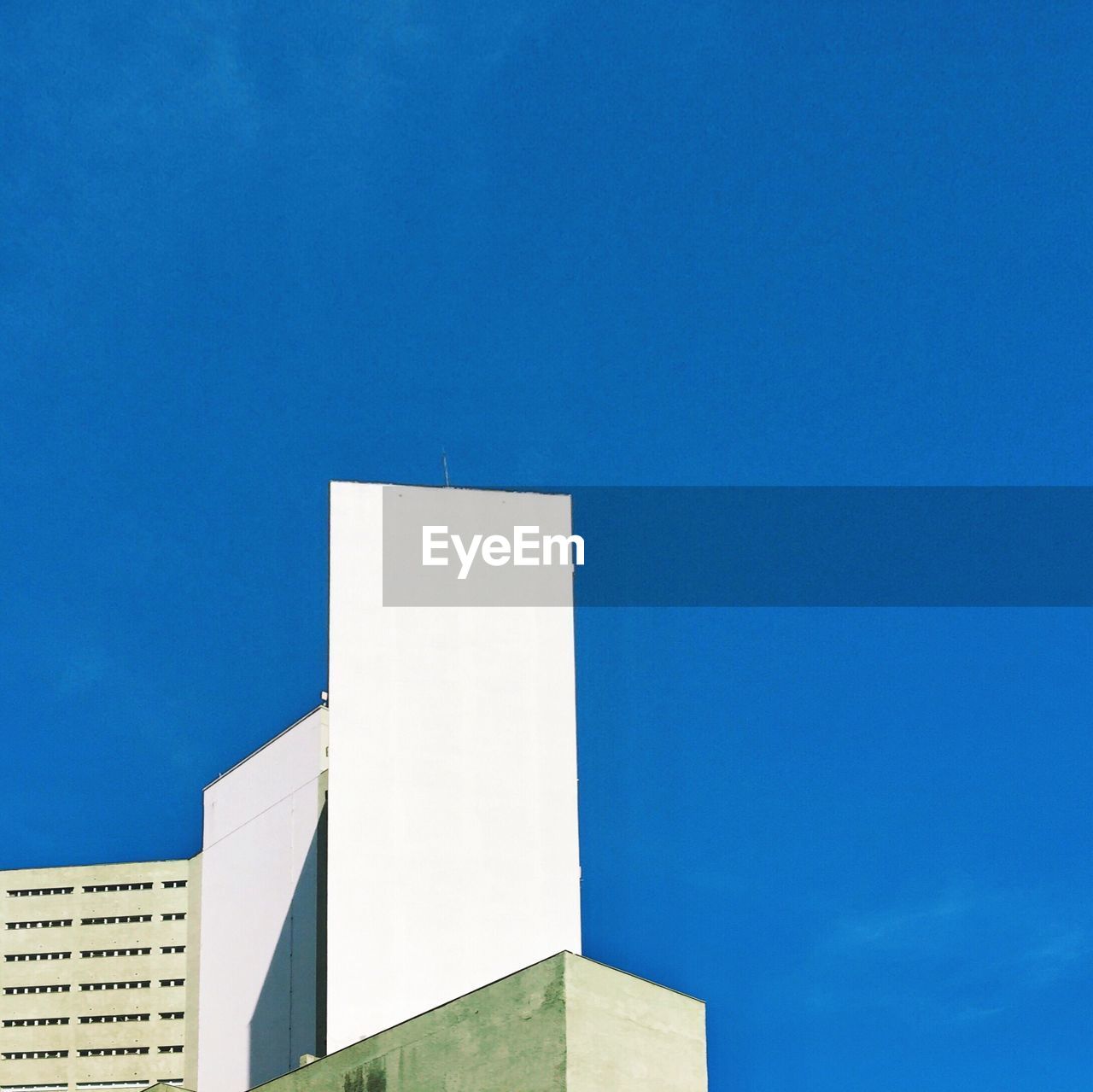 LOW ANGLE VIEW OF BUILDINGS AGAINST CLEAR BLUE SKY