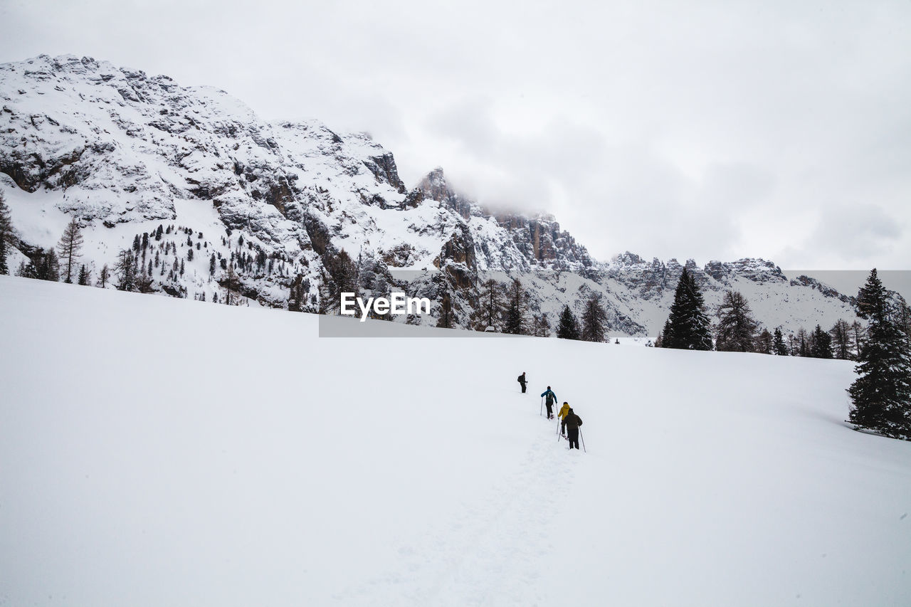 People skiing on snow covered mountain against sky